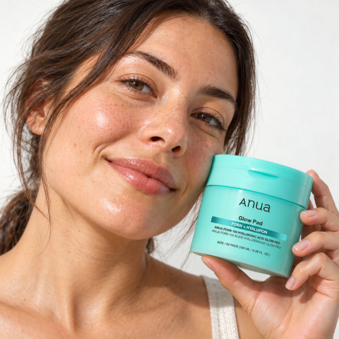 Smiling woman holding the Anua Glow Pad PDRN + Hyaluron tub next to her face