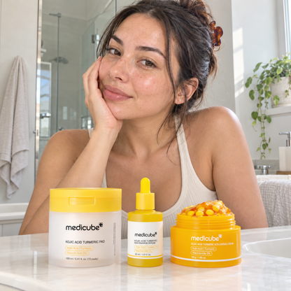 Woman smiling beside the Medicube Kojic Acid Turmeric pad, serum and cream