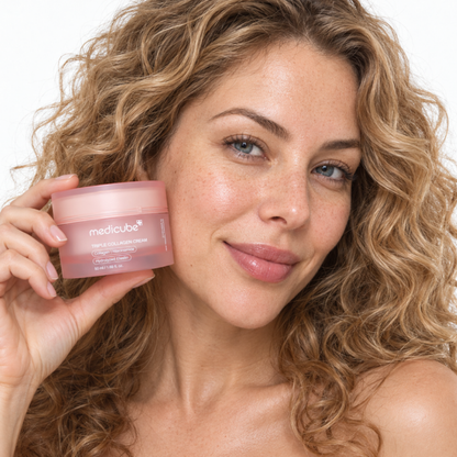Smiling woman holding Medicube Triple Collagen Cream jar beside her cheek