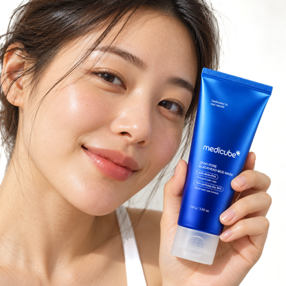 Smiling woman holding Medicube Zero Pore Blackhead Mud Mask tube beside her face